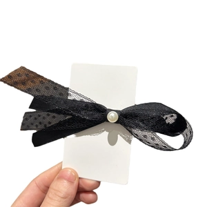 Pince à cheveux élégante en dentelle noire avec nœud et perle sur carte de support