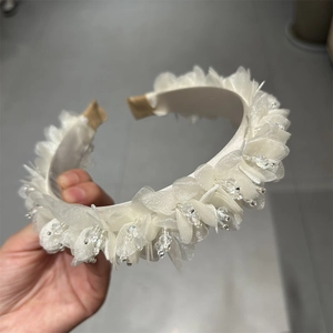 Detail der weißen Netzblütenblätter und Kristallperlen auf einem floralen Stirnband