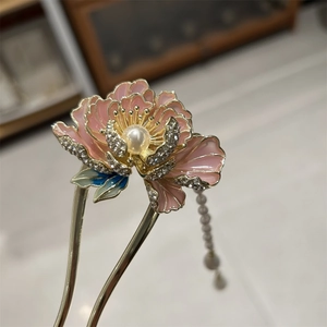 Détail d'une épingle à cheveux pivoine en émail rose avec bords dorés et pompons de perles