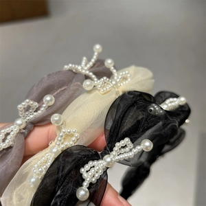 Detailed close-up of textured organza headbands with hand-stitched faux pearls