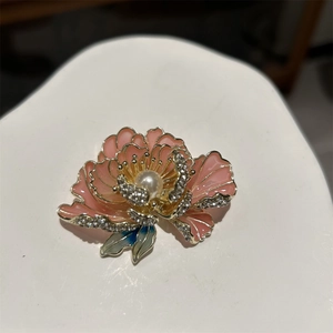 Détail de broche pivoine en émail rose avec perle centrale et accents de strass brillants