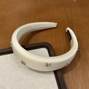 Dettaglio ravvicinato del cerchietto imbottito color crema con strass a stella e tag fatto a mano