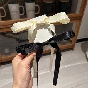 Close-up of elegant black and cream satin ribbon bow hair clips with a silky smooth finish