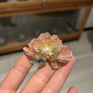 Gros plan détaillé de la broche fleur de pivoine rose avec perles et finition émaillée