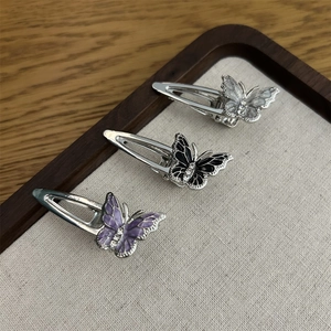 Detailaufnahme von drei farbenfrohen Strass-Schmetterlings-Haarspangen in einem Holztablett