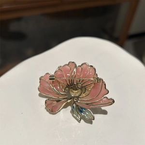 Vue arrière de la broche fleur rose avec épingle dorée et détail de feuille bleue