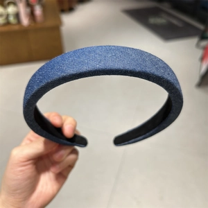 Detailed close-up showing the textured blue denim fabric and wide padded style of the headband