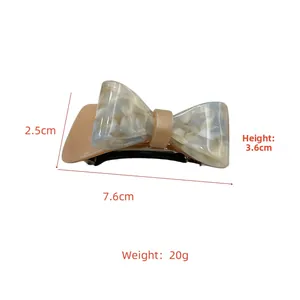 Detailed view of cream marble acetate bow hair clip with silver spring mechanism