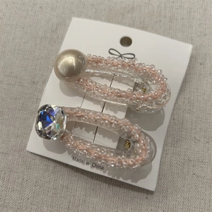 Set di fermagli per capelli con perle champagne e cristalli colorati su carta bianca
