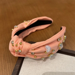 Détail du serre-tête rose à nœud large avec perle de cœur, cristaux et perles