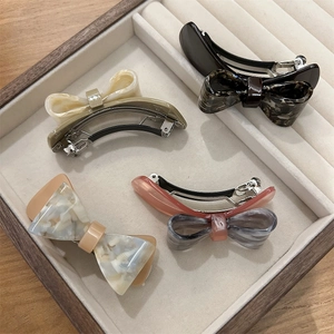 Detail of acetic acid bow hair clips with marble textures on a jewelry tray