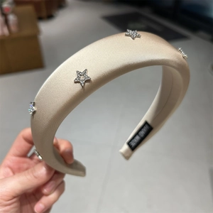 Dettaglio del cerchietto fatto a mano in raso oro champagne con stelle brillanti