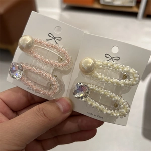 Dettaglio di fermagli per capelli con perle rosa e beige e strass lucidi per acconciature