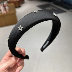 Dettaglio di un cerchietto in raso nero fatto a mano con decorazioni a stella di strass