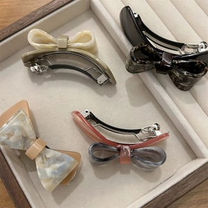 Elegant acetate bow hair clips set with marble textures in a velvet jewelry tray