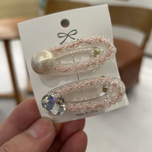 Dettaglio di fermagli per capelli con perle e cristalli e bordo di perline rosa