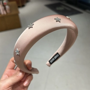 Dettaglio del cerchietto in raso rosa con stelle di cristallo e etichetta fatta a mano