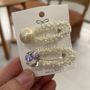 Dettaglio di set di fermagli per capelli con perle e strass su carta espositiva