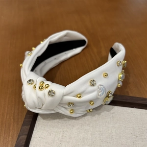 Détail du bandeau noué blanc orné de strass étincelants et de perles dorées élégantes