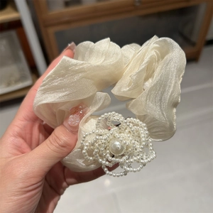 Detail of cream organza hair scrunchie with large white pearl camellia flower ornament