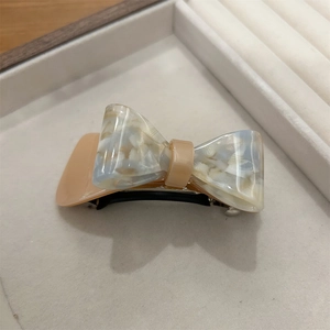 Detailed close-up of marble pattern acetate bow hair clip on a velvet jewelry box