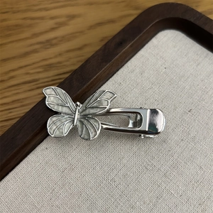 Nahaufnahme der silbernen Haarspange mit Schmetterlingsflügeln und weißem Muscheldetail