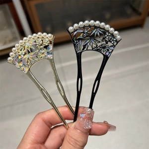 Gros plan de pics à cheveux vintage avec motif floral en émail et perles blanches