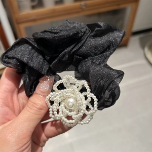 Detailed macro view of black tulle scrunchie with white pearl flower decor