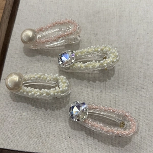 Dettaglio di quattro fermagli per capelli fatti a mano con perle e cristalli su tessuto
