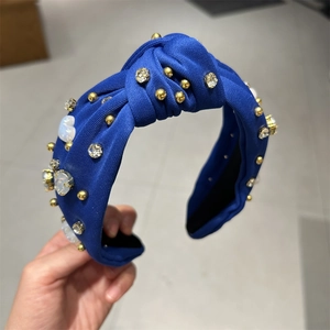 Détail d'un bandeau torsadé bleu roi avec perles dorées, pierres blanches et strass