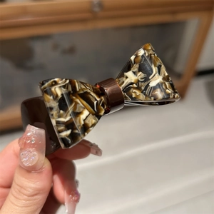 Detailed close-up of a tortoiseshell acetate bow hair clip with glossy polished finish