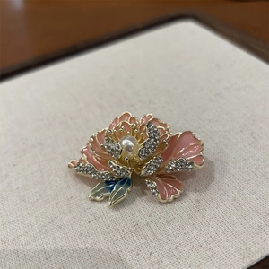 Détail de la broche pivoine rose avec perle blanche et cristaux brillants sur métal doré