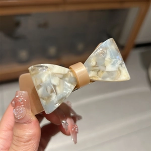 Detail of acetate bow hair clip showing pearlescent texture and spring mechanism
