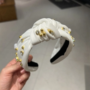 Détail du bandeau noué blanc orné de perles dorées et de strass brillants chic