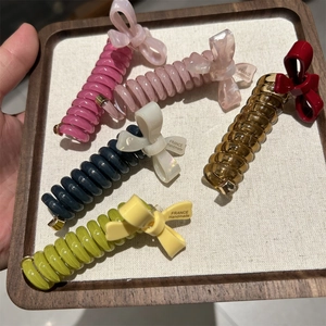 Detail of five colorful spiral bow hair clips with France Handmade labels in a wooden tray