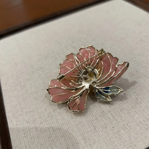 Détail de la broche pivoine en émail rose avec épingle en métal doré et motifs filigranes