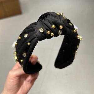 Détail du serre-tête noué noir avec perles, cristaux et billes dorées sur tissu