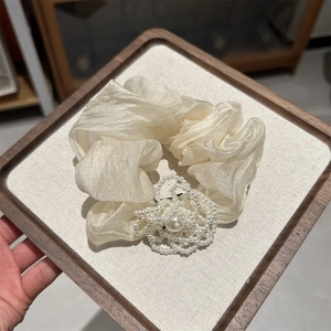 Close-up of cream pleated hair scrunchie with elegant pearl flower decoration detail