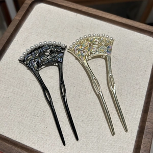 Détail de deux épingles à cheveux vintage avec motifs d'éventail et perles blanches