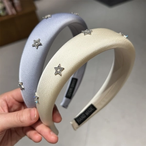 Dettaglio di cerchietti in raso fatti a mano con strass a stella scintillanti in blu e beige