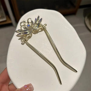 Detailed close-up of a golden U-shaped hair pin featuring a sparkling crystal swan motif