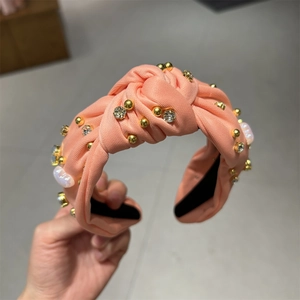 Détail du serre-tête torsadé rose avec perles dorées et strass brillants décoratifs