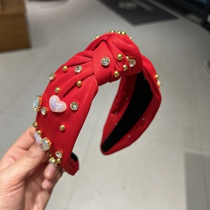 Détail du serre-tête noué rouge avec strass, perles dorées et gemmes de cœur