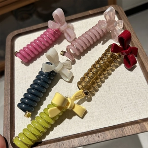 Detail of five colorful spiral telephone wire hair ties with handmade bow decorations