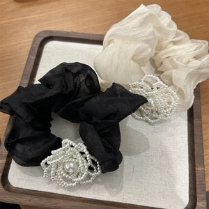 Detailed view of camellia pearl hair scrunchies in elegant black and pearl white fabrics