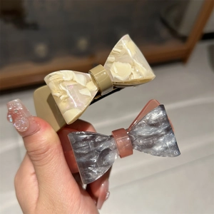 Close-up of marble pattern acetate bow hair clips with spring clips in neutral tones