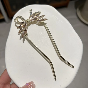 Detailed macro of golden U-shaped hair pin with champagne pink crystal bow design