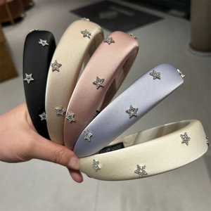 Dettaglio di cerchietti in seta con strass a stella ed etichetta Hand Made