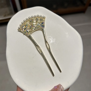 Détail d'une épingle à cheveux éventail dorée avec perles et motifs floraux en émail