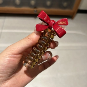 Detail of red bow hair tie with France Handmade text and amber spiral telephone cord hair ring